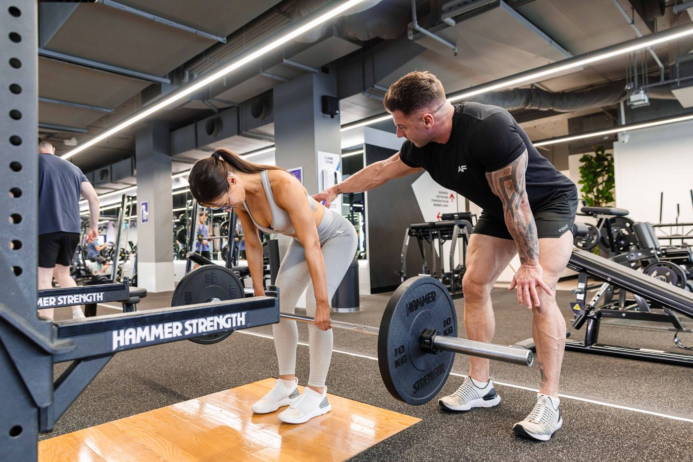 Dominic coaching a client through a hip hinge, hand on lower back